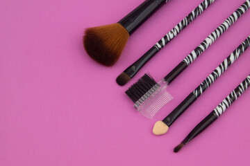 Set of makeup brushes on pink background with copy space