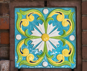 Abstract ornamental background. Fragment of old building wall, with ornate glazed tiles. white flower on a turquoise background. for architecture design. - 376032496