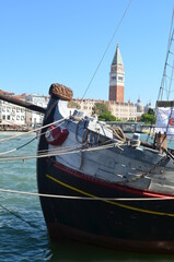 
San Marco bell tower in Venice with historical wooden boat prow in the foreground