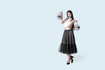 Young beautiful brunette girl in dark box pleated midi skirt posing in studio. Woman balancing...
