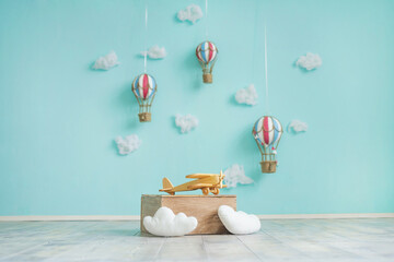 Toy hot air balloons, airplane and clouds on a blue wall. Children's room decor in the style of travel.