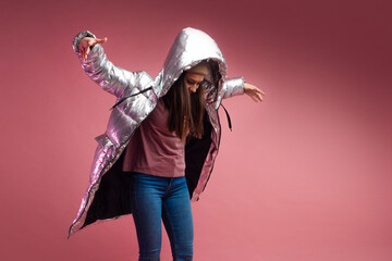 fashionable and modern young woman in a puffy light down jacket throws a hood over her head.