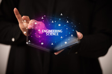 Fototapeta na wymiar Businessman holding a foldable smartphone with ENGINEERING SCIENCE inscription, new technology concept