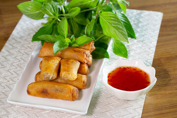 Fried Spring rolls on white dish with sweet suace in the white bowl