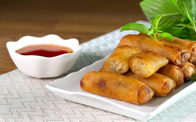 Fried Spring rolls on white dish with sweet suace in the white bowl
