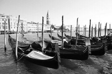 
black and white panorama of Venice with row of gondolas in the foreground