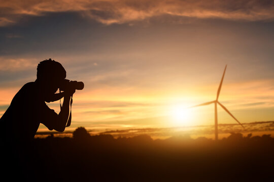Silhouette of photographer taking pictures a sunset background.
