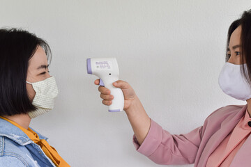 Women hand holding infrared forehead thermometer to check body temperature. Concept of protect from...