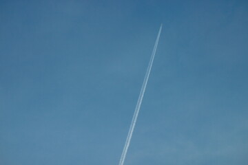 The white trail of a plane in the blue sky.