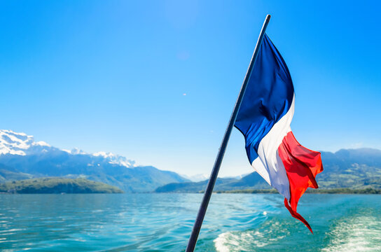 French flag on the background of the French alps surrounding Lake Annecy
