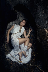 A girl in a white dress lies on the scorched earth. Lies between two trees. A doomed and empty look.