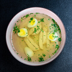 Soup with noodles, chicken, egg and dill on a dark background in a plate