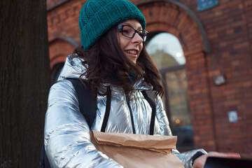 young woman in warm clothes with a paper bag in her hands, going shopping.