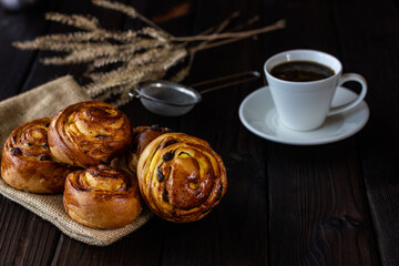 Buns on a light wooden background that lie on plates with a small cup of hot coffee