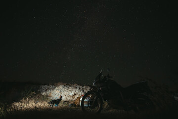 Obraz premium Night camp on the top of the mountain, Camping with tent and motorcycle, Overnight in the wild. Starry sky with the milky way. Starfall. The concept of an active lifestyle and extreme hobbies.