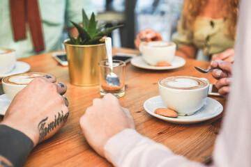 Young friends drinking cappuccino inside vintage bar - Trendy people doing meeting at breakfast - Main focus on right bottom cup