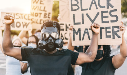 People from different culture and races protest on the street for equal rights - Demonstrators wearing face and gas masks during black lives matter fight campaign - Focus on black gas mask