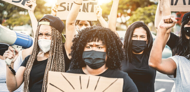 People from different culture and races protest on the street for equal rights - Demonstrators wearing face masks during black lives matter fight campaign - Focus on right girl face - Powered by Adobe