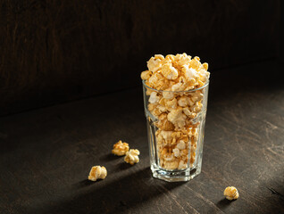 Appetizing crispy popcorn in a glass on a dark background