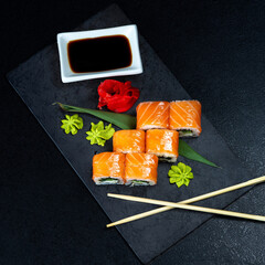 Sushi roll with salmon, smoked eel, avocado, cream cheese on black background. Sushi menu. Japanese food.