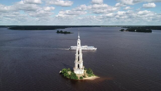 Flight over an island with an abandoned bell tower on the Volga River and cruise ships. Drone view for an abandoned chapel on the island. Travel along the golden ring of Russia. Cruise along the Volga