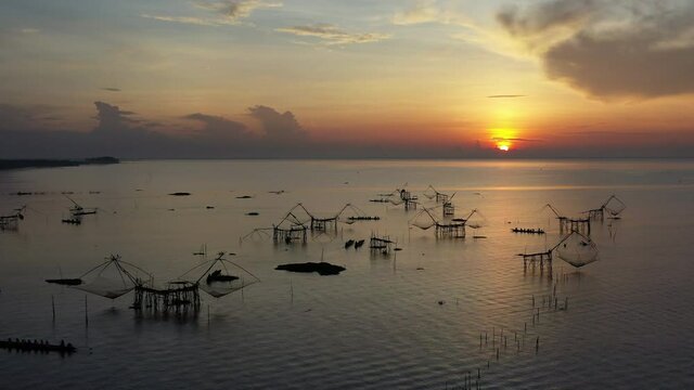 4K drone footage of pakpra fisherman village and traditional fishing net made by bamboo in sea with tourism boat sightseeing in morning located in Phatthalung province Thailand