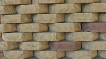 decorative brickwork with a volumetric texture of beige light brown stone, a fragment of a brick fence or a sand-colored facade