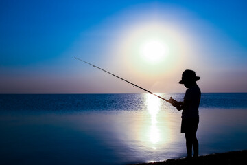 A Happy child fisherman fishing by the sea on nature silhouette travel