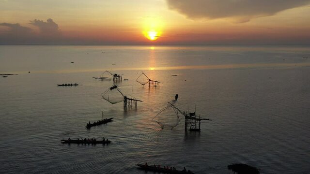 4K drone footage of pakpra fisherman village and traditional fishing net made by bamboo in sea with tourism boat sightseeing in morning located in Phatthalung province Thailand
