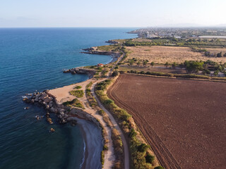 Fototapeta na wymiar Aerial view of a rocky coastline near a plowed soil field at Jardi de Sol de Riu, Vinaros, Spain.
