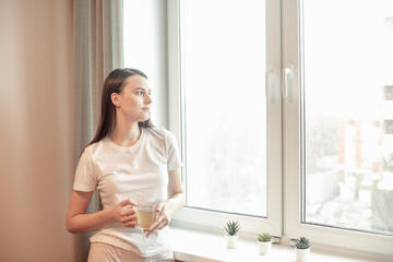 Fototapeta na wymiar Beautiful woman drinking morning tea behind window