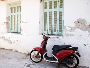 altes rotes motorrad an einem verlassenen Haus unter geschlossenen fenstern in der mediterranen mittagshitze