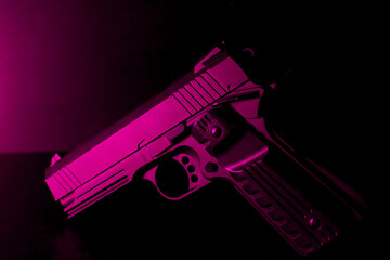 Black pistol with purple tones in a black background
