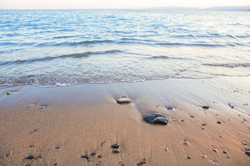 Sea surf on a sandy shore with pebbles.
