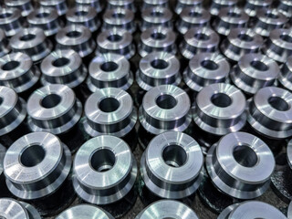 batch of shiny round steel parts background, close-up with selective focus and blur