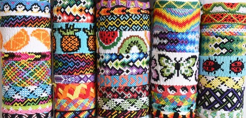 Many tied woven DIY friendship bracelets handmade of embroidery bright thread with knots. Alpha and normal patterns