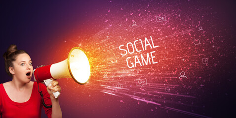 Young woman yelling to loudspeaker with SOCIAL GAME inscription, social networking concept