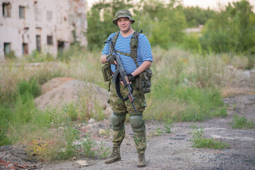 Professional airsoft player in a vest stands with a gun