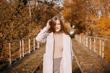 beautiful long-haired woman walks through the autumn streets. Railway, autumn, woman in a coat.