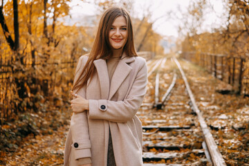 beautiful long-haired woman walks through the autumn streets. Railway, autumn, woman in a coat.