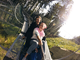 Summer toboggan run rodelbahn with many curves on a mountain. Alpine coaster in summer and autumn beautiful landscapes. Fast ride fun of young couple travelling