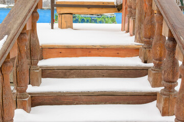 The wooden steps are covered with new snow. Balustrade. Concept of the first snow in the winter season, the onset of cold weather. 