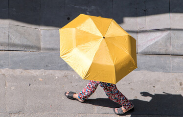 The walker on the street of the city is hiding under a parasol, Ho Chi Minh city. A woman wearing a...