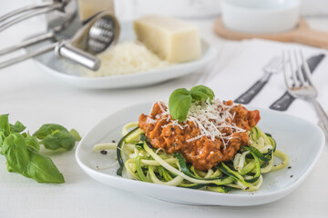 Zoodles bolognese: zucchini noodles with meat or vegan soy meat sauce and parmesan. For low carb, keto, paleo nutrition.