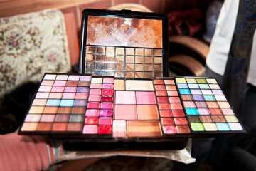 Isolated make-up set palette in a home ambient background. The make-up set is used, and the mirrors...