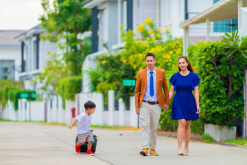 Travel and Tourism Concept - Family of tourists carrying suitcases near home.