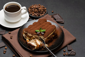 portion of Classic tiramisu dessert and cup of fresh espresso coffee on concrete background