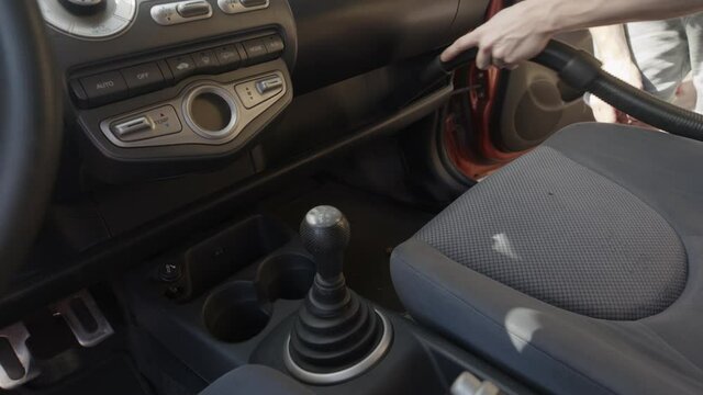 Man cleaning dirty car interior with vacuum cleaner