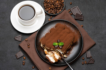 portion of Classic tiramisu dessert and cup of fresh espresso coffee on concrete background
