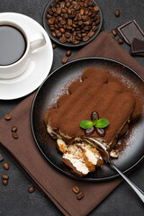 portion of Classic tiramisu dessert and cup of fresh espresso coffee on concrete background